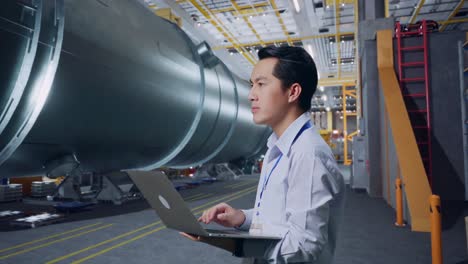 engineer working on laptop in a factory