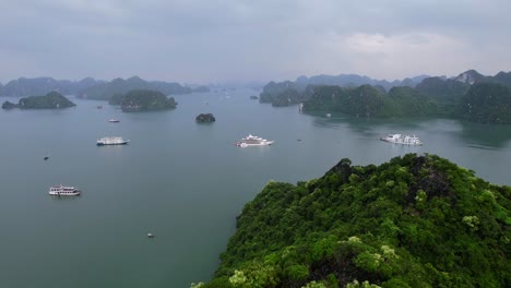 Vuelo-Aéreo-Sobre-Montañas-De-Piedra-Caliza-Que-Revelan-Cruceros-En-La-Bahía-De-Ha-Long-Vietnam-En-Un-Día-Nublado-Que-Rodea-El-Agua-Tropical