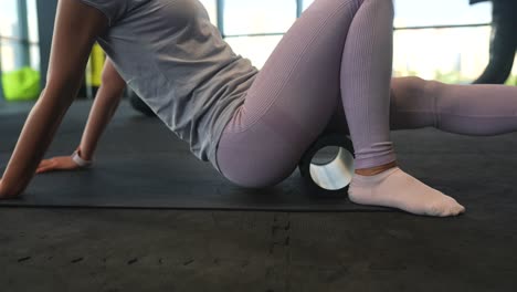 mujer que usa un rodillo de espuma para estirar las piernas