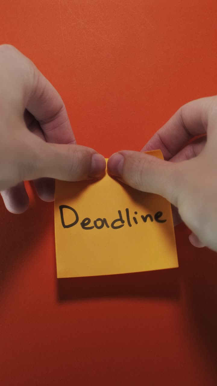 Portrait shot of a yellow sticky note reading "Deadline" on an orange background