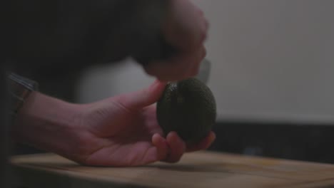 Hands cutting an avocado on a wooden board
