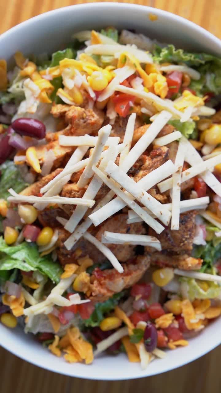 A colorful chicken salad topped with cheese, close up shot