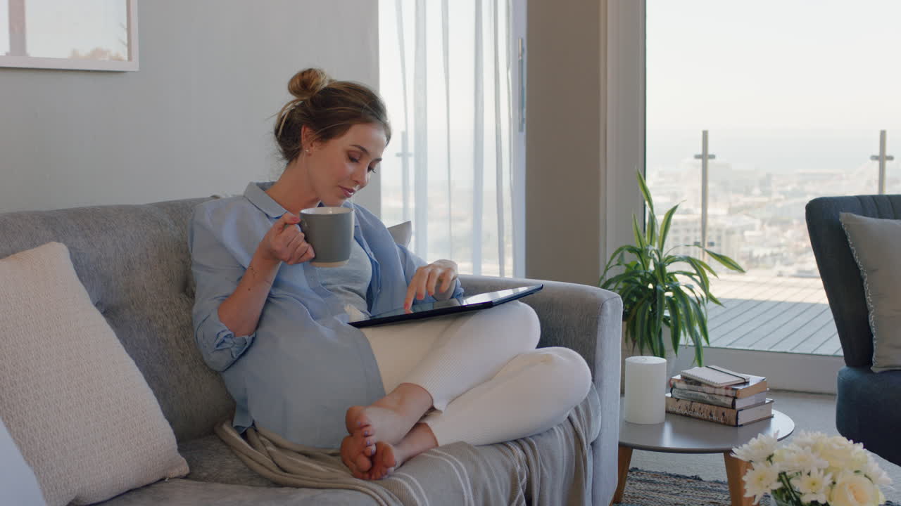 Beautiful young woman using digital tablet computer relaxing on couch ...