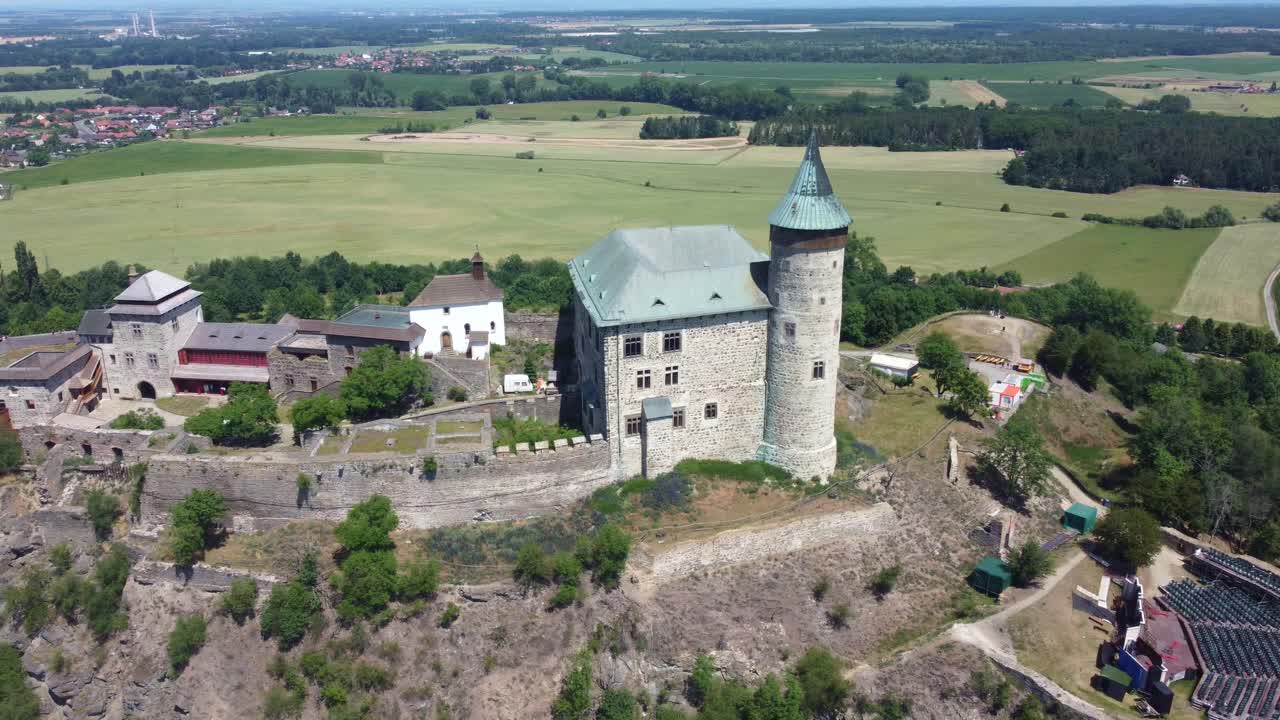 Drone tracking left across establishing Kuneticka Hora Castle nestled in vast green fields, Czech Republic