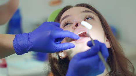 female dentist takes out cotton tampon from open patient mouth