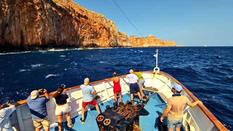 people sailing on a boat taking pictures of a cliff at kissamos port west of the island of crete, greece