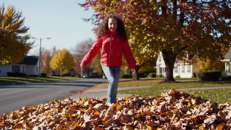child jumping in an autumn leaf pile