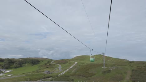 green cable car gondola sightseeing transportation passing across scenic mountain valley hillside