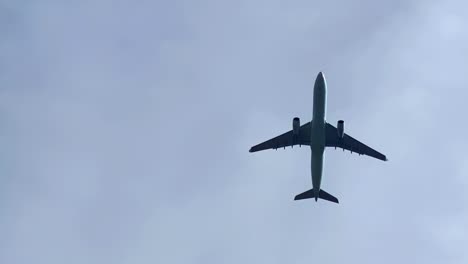 a silhouette of an airliner aircraft flying on a cloudy day.