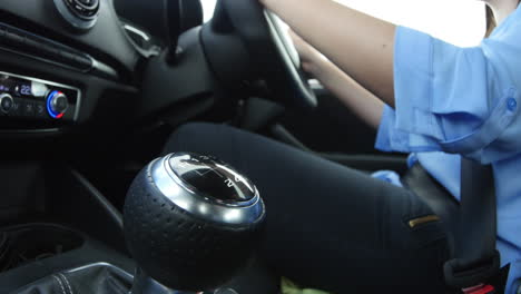 young woman driving in a car, gear change close-up