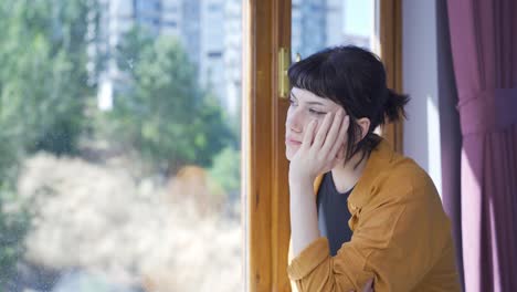 Pensive-young-woman-is-watching-outside.