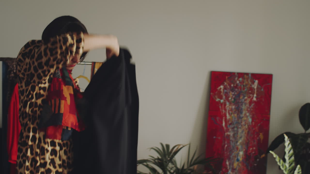 트랜스젠더 남자가 집을 떠나기 전에 스카프와 코트를 입고 있습니다.