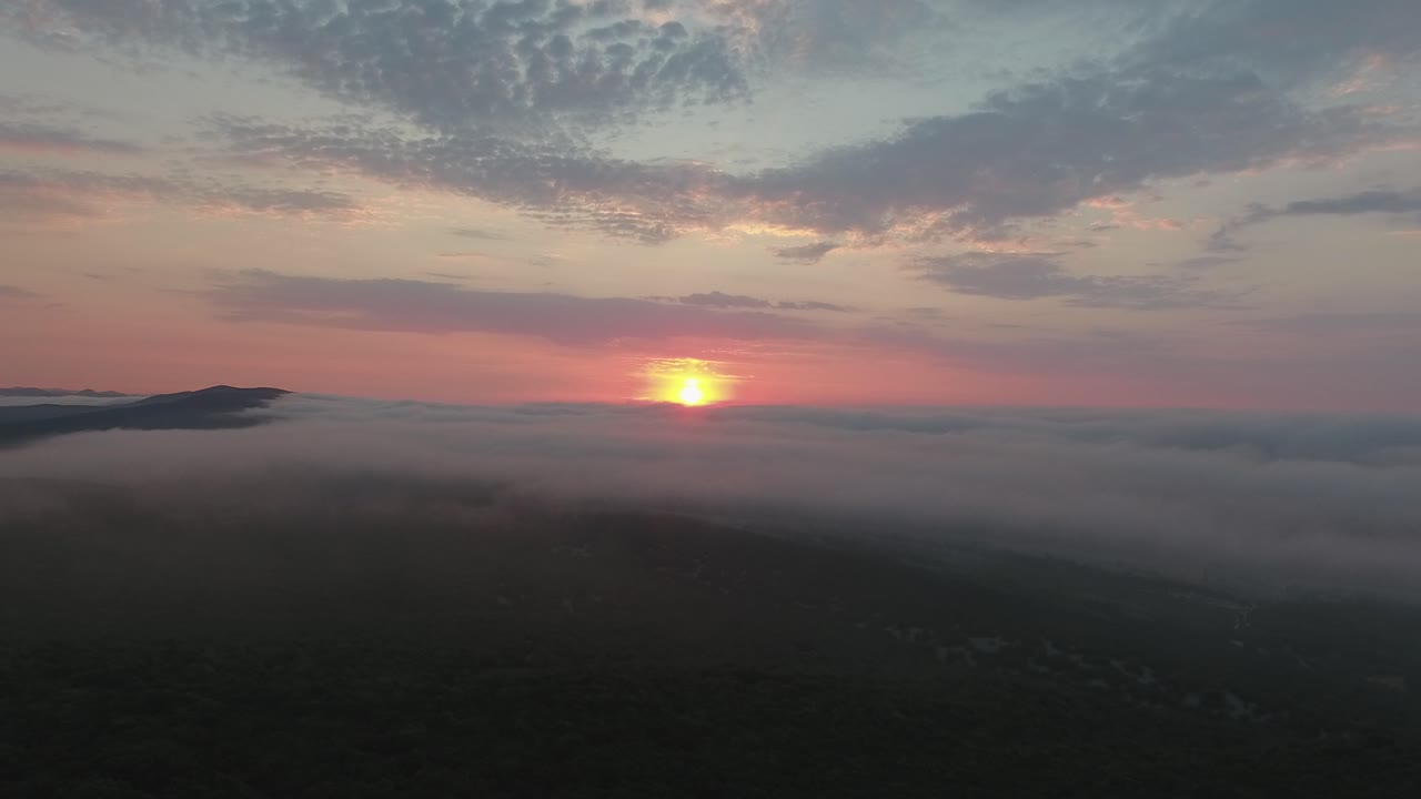 Amazing drone shot above scrublands and clouds  during sunrise. Location France