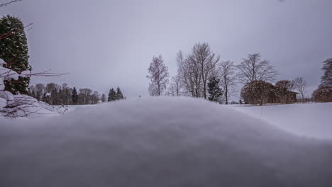 timelapse of a snowy landscape with a lot of snow and some trees at dusk