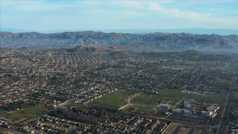 aerial drone shot of the city of elsinore surrounded by the mountain range, california, usa