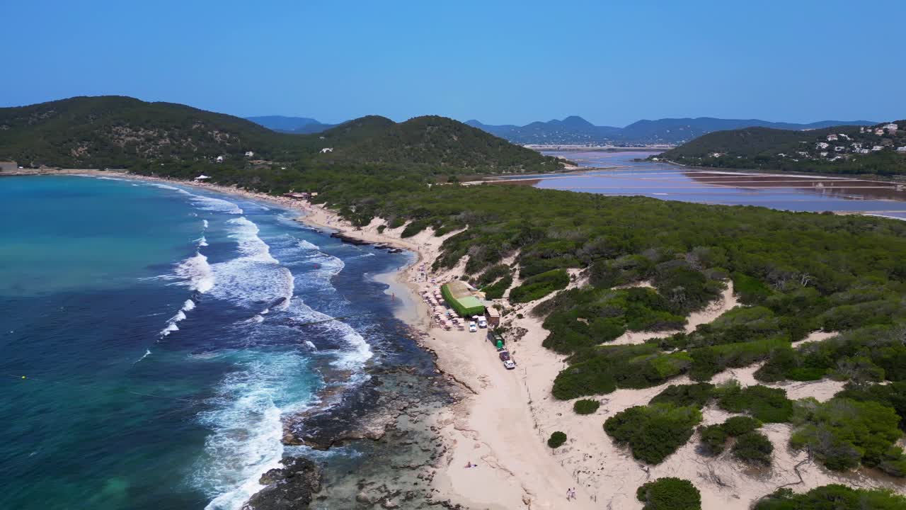 Turquoise waves crashing on the rocky coast of Ses Salines beach with the ancient watchtower. Fantastic aerial view flight panorama overview drone