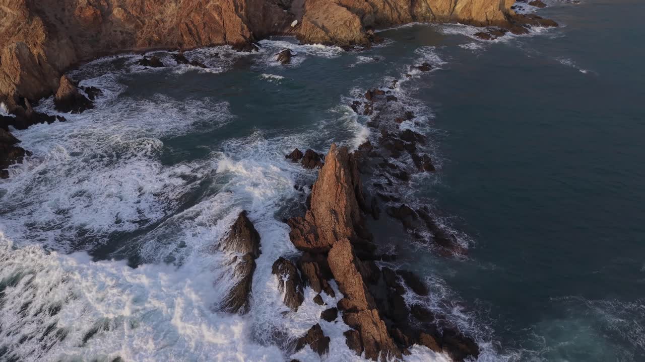 Spettacolari riprese aeree di potenti onde oceaniche che si infrangono contro le spettacolari formazioni rocciose della Scogliera delle Sirene all'alba.