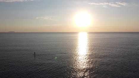 Luftaufnahme-Eines-Paddelboarders-Mitten-Im-Meer-Bei-Sonnenaufgang