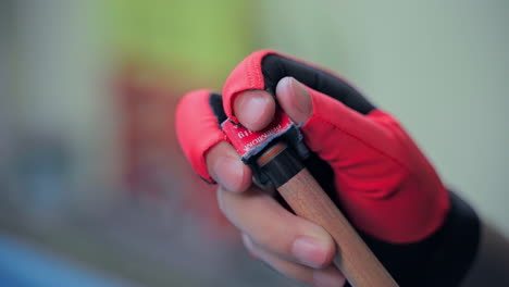 man's hand with red pool glove wipes a cue with chalk ready to start game