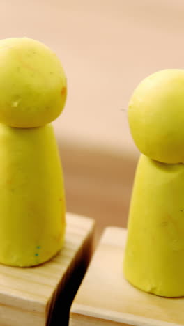 yellow figurines on wooden blocks in a row and red figurine fallen on ground