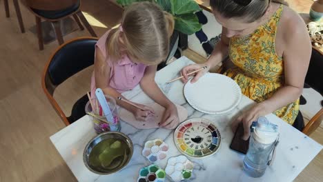 madre e hija pintando una cerámica