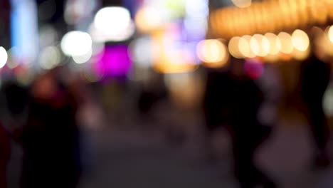 personas fuera de foco caminando bajo las luces de la ciudad por la noche