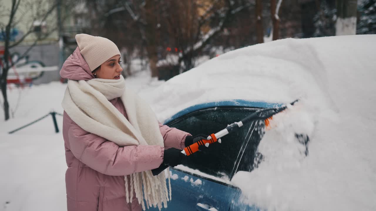 mujer quitando la nieve del coche en invierno