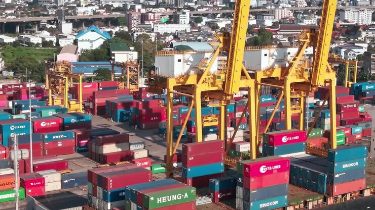 Container cranes operate over colorful shipping containers in Bangkok