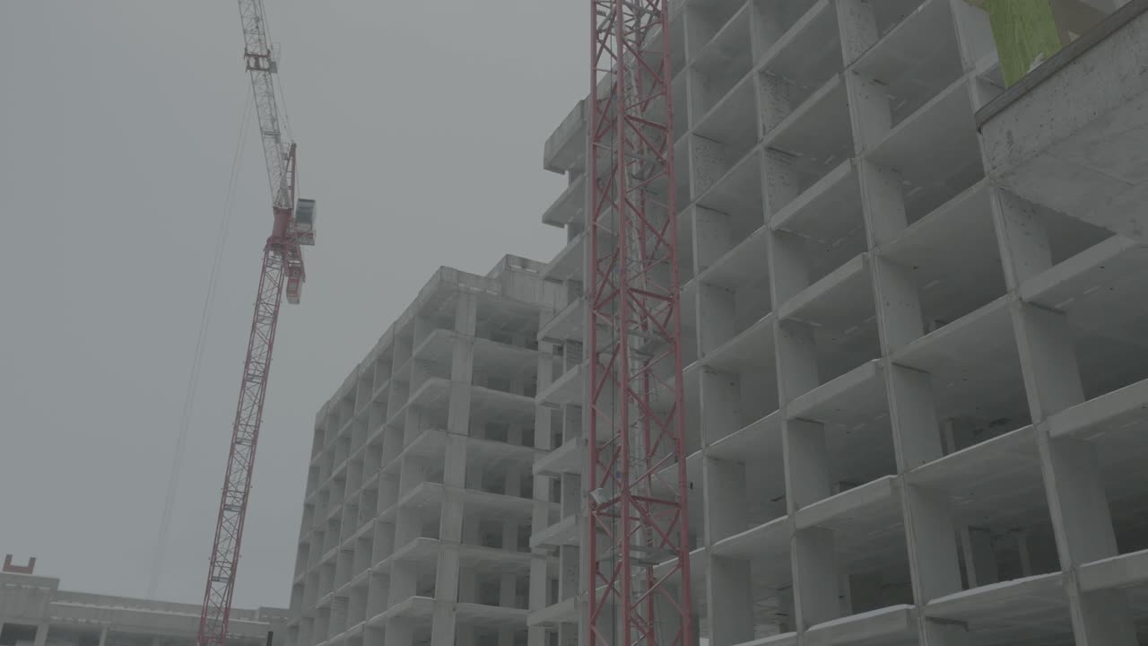 sitio de construcción en invierno con grúas y edificios de hormigón
