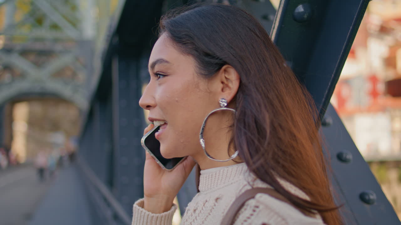 Cheerful brunette talking cell call sharing good news at iron bridge closeup