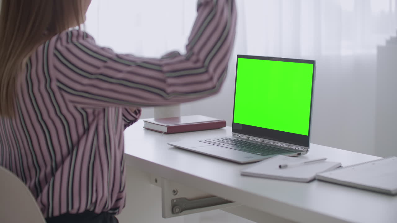 una mujer joven está hablando por videoconferencia en una pantalla verde de portátil para la tecnología de llave cromática gesticulando con las manos