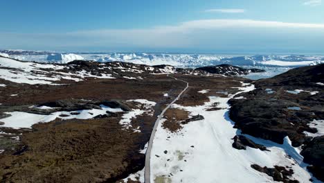 Amazing-drone-aerial-of-scenic-road,-journey-to-Icefjord-with-massive-icebergs