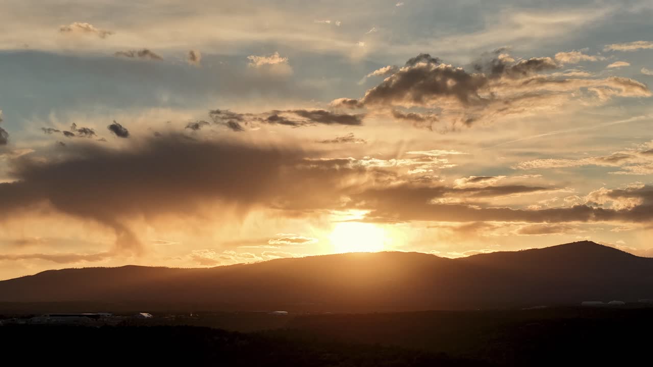 Un hiperlapse cinematográfico 4K con dron captura nubes dinámicas y cambiantes que se desplazan por un vibrante cielo al atardcer. La cambiante luz del atardecer y el movimiento envolvente de las nubes proporcionan un fondo atmosférico