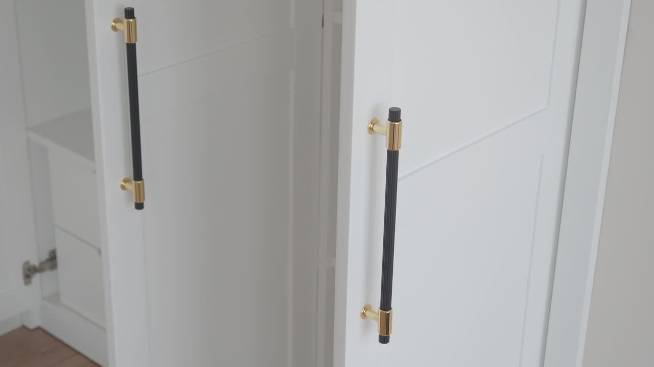 закрытие белых дверей шкафа с золотыми и черными дверными ручками