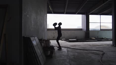 african american man exercising with medicine ball in an empty urban building