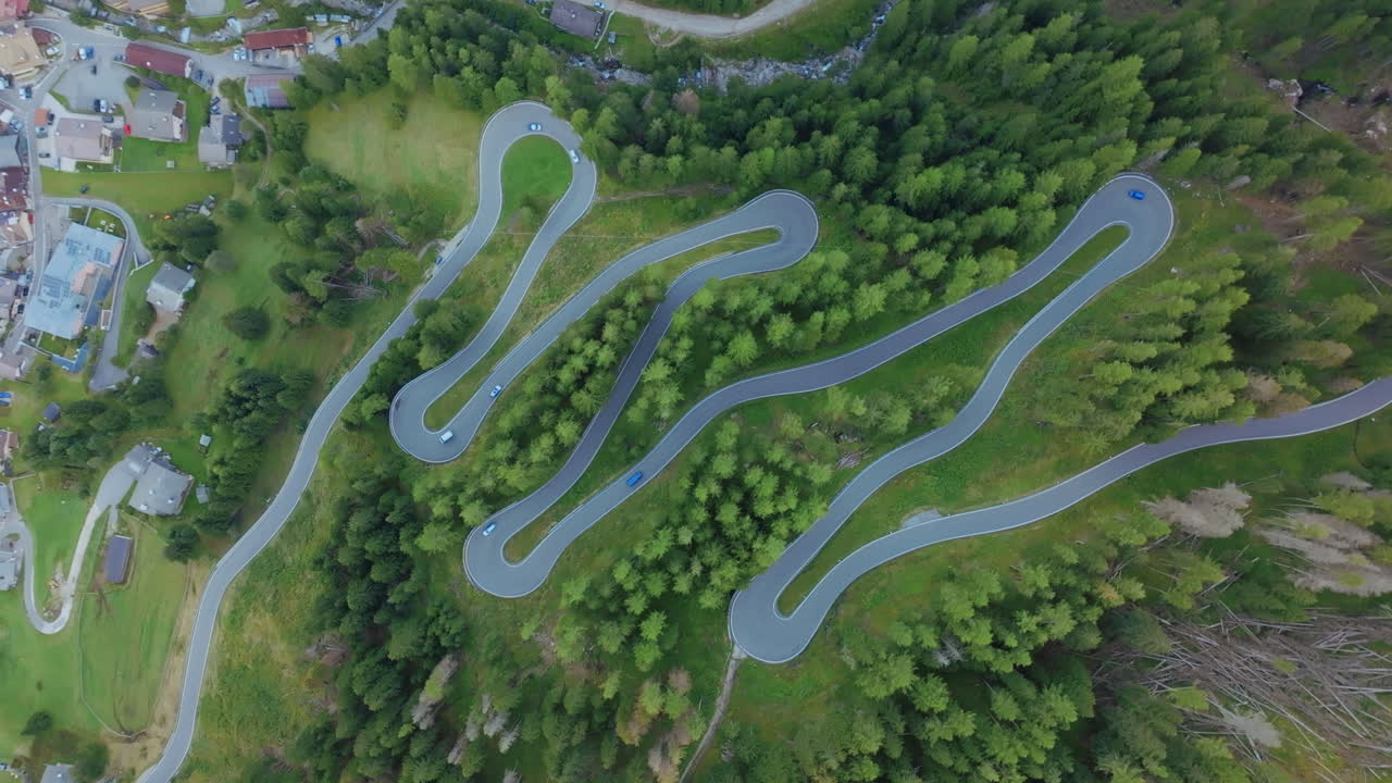 Cars quickly traveling up and down switchbacks in the Dolomites in Italy.