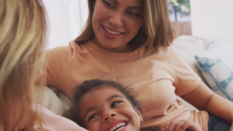 multi-generation female hispanic family relaxing on sofa at home