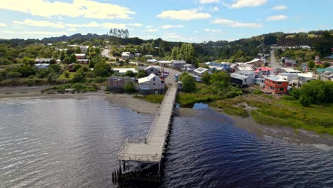 Drones-Aéreos-Vuelan-Sobre-El-Puente,-Pequeño-Pueblo-En-El-Lago-Huillinco-Chiloé-Paisaje-Patagónico-Chileno,-Horizonte-De-Verano-Y-Colinas-Verdes-De-La-Isla