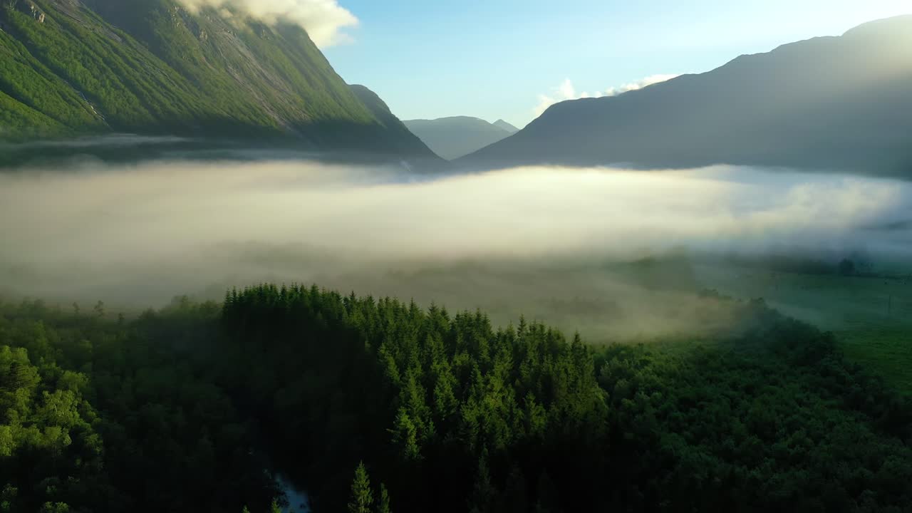 Morning mist over the valley among the mountains in the sunlight. Fog and Beautiful nature of Norway aerial footage.