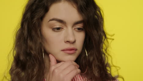 pensive woman thinking in studio. portrait of serious girl thinking on yellow