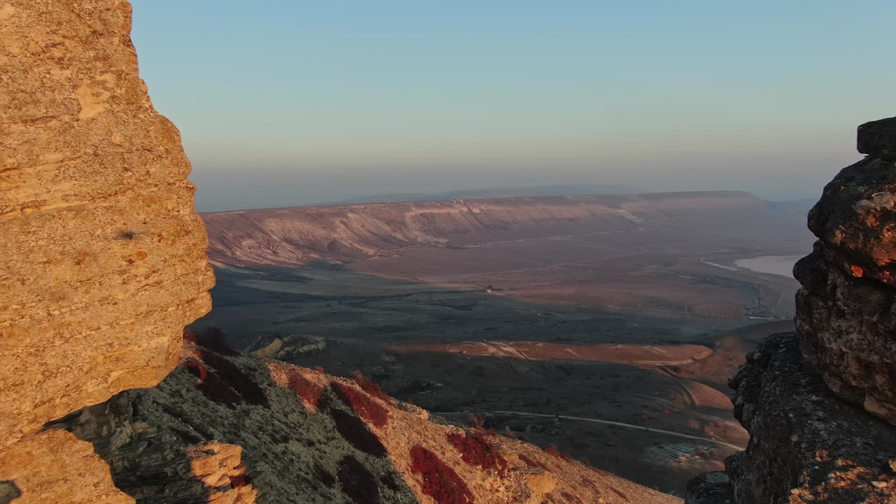 vista aérea. volando a lo largo de las rocas inundadas por la puesta de sol en el fondo del valle y siluetas de montañas en la distancia. crimea.