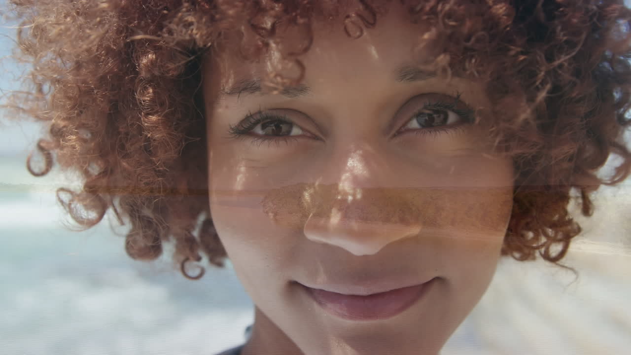 animación de una mujer biracial feliz con la cara sobre el paisaje marítimo