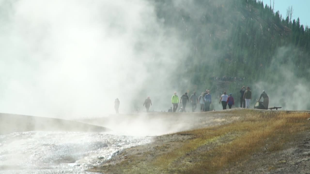 los visitantes de las magníficas aguas termales prismáticas del parque nacional de yellowstone quedan oscurecidos por la niebla humeante que sale de los estanques supercalentados.