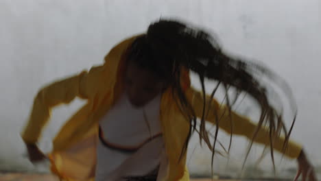 dancing-woman-young-mixed-race-street-dancer-performing-freestyle-hip-hop-moves-enjoying-modern-dance-expression-practicing-in-grungy-warehouse-wearing-yellow-jacket