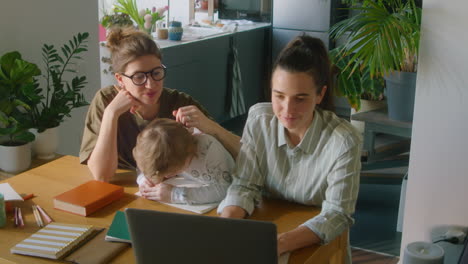 boy studying online at home with help of lesbian mothers