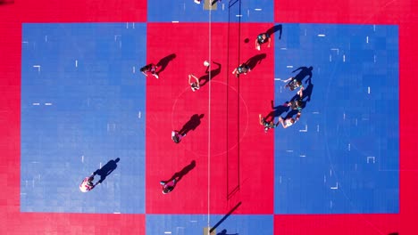 birdseye aerial view of people playing volleyball on red blue outdoor court