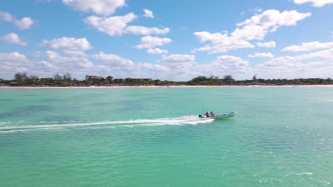 tiro de drone rastreando un bote que pasa por el marco en las hermosas aguas turquesas frente a la costa de la isla tropical de holbox durante un hermoso día soleado en méxico filmado en 4k