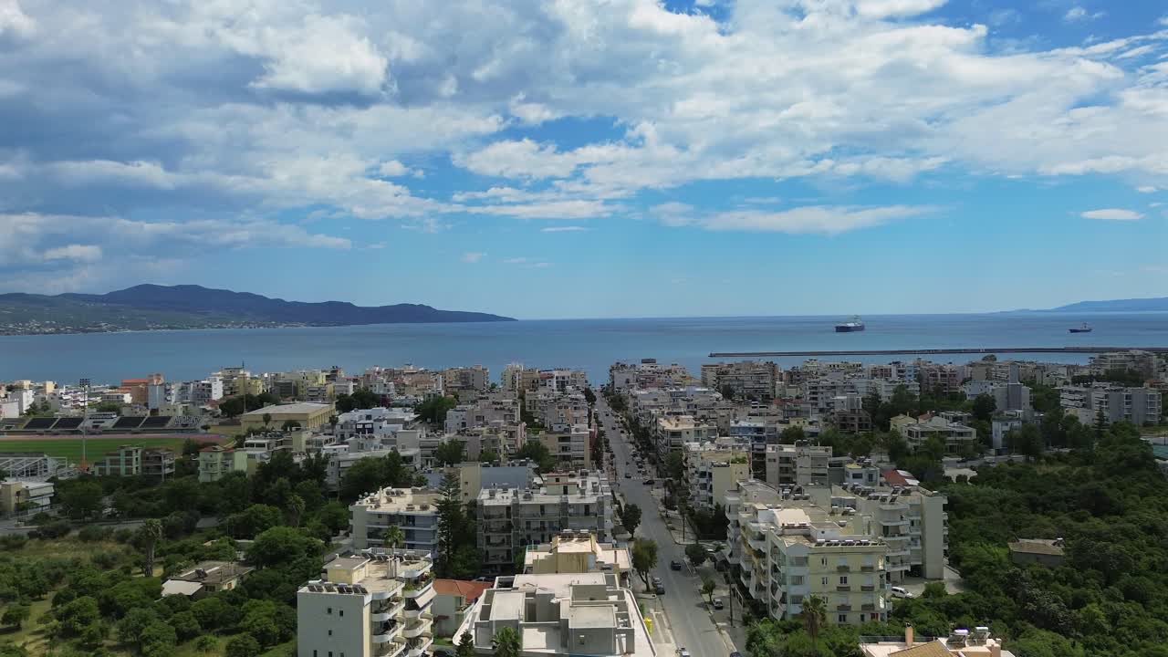 Aerial high angle wide pan footage, Iroon street at Kalamata, leading to the sea , Messinian bay on the background, blue sky with beautiful white cloud formations 4K