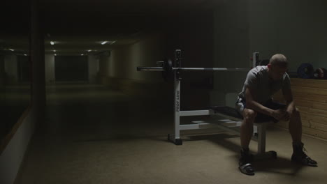 man sitting on bench press in dark gym