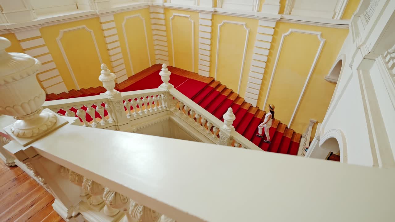 Graceful woman climbs palace stairs as camera moves in through carved rail